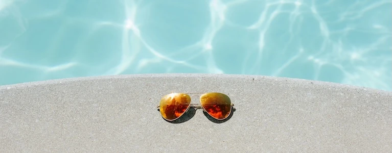 pair of sunglasses beside a swimming pool